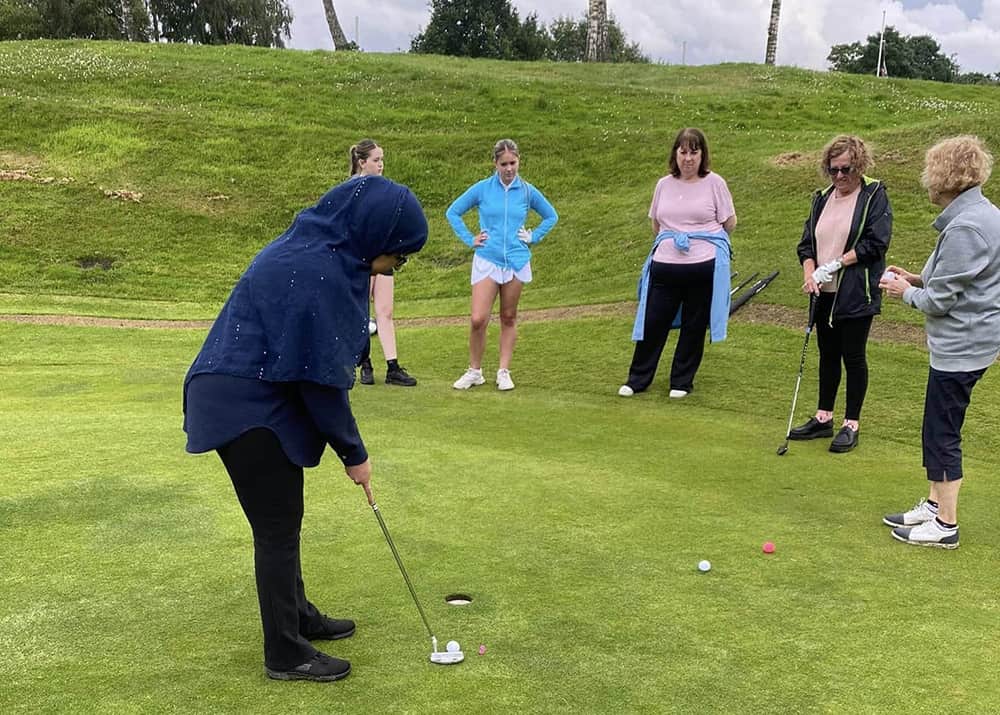 women being taught to play golf